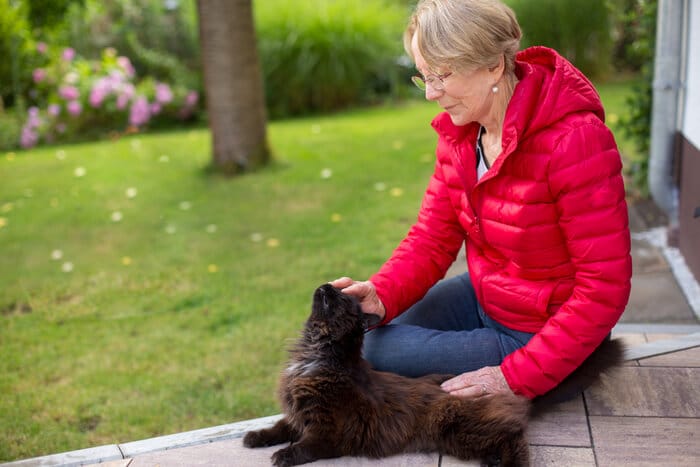 Una persona che cerca all'aperto con un'espressione preoccupata, probabilmente alla ricerca di un gatto smarrito.