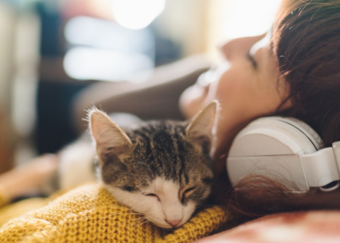 Un'immagine accattivante che ritrae una donna e il suo gatto che condividono un momento musicale.