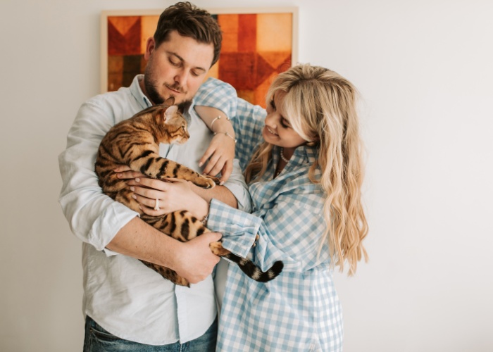 Deliziosa immagine che ritrae una coppia adorabile che condivide un momento delizioso con il proprio gatto, raffigurando la gioia e l'amore che gli animali domestici possono portare nelle relazioni.