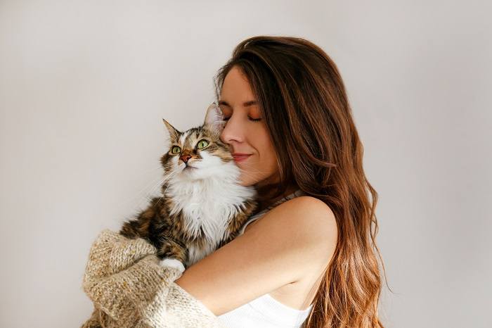 L'immagine ritrae una scena commovente in cui un gatto è comodamente adagiato accanto a una donna.