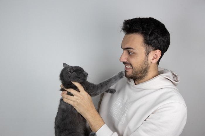 Un'immagine che raffigura un uomo che interagisce con un gatto.