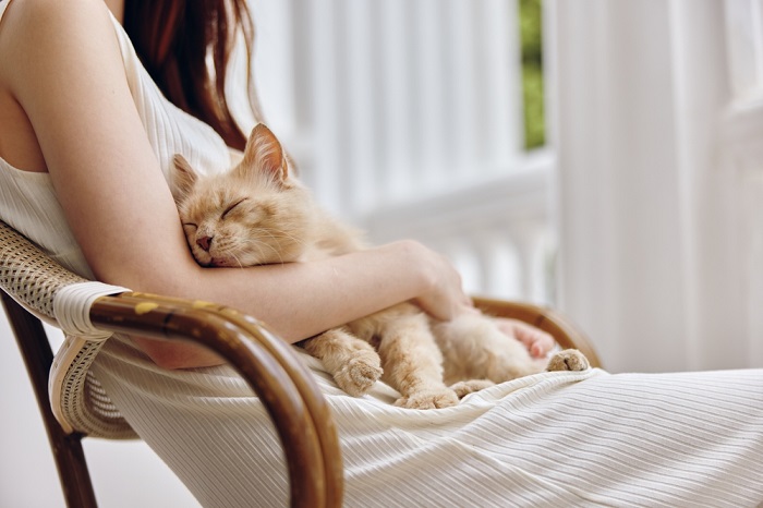 Una donna che si gode un momento di pace con il suo gatto, un legame sereno e commovente tra uomo e felino.