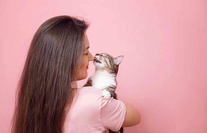 Immagine che cattura una dolce interazione: un gatto curioso lecca teneramente la mano di una bambina felice, evidenziando il legame tra loro.