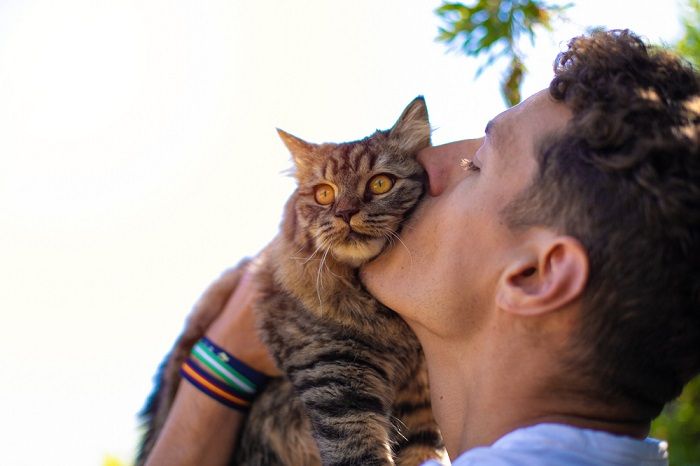 uomo in giardino che abbraccia e bacia un gatto