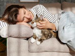 Portrait of young woman holding cute Siberian cat with green eyes