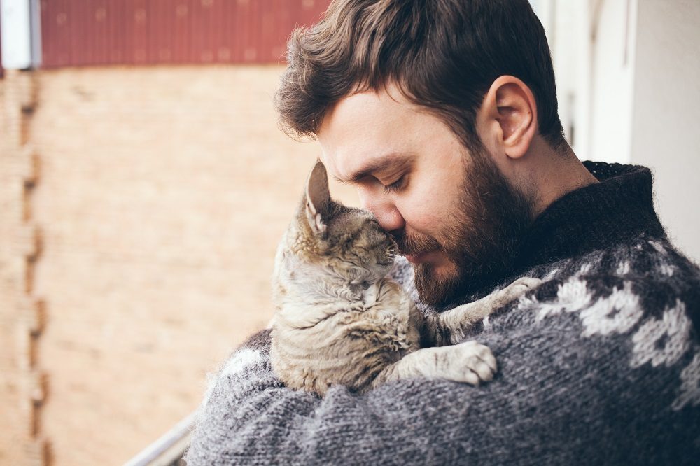 ritratto di gatto felice con gli occhi chiusi e giovane uomo